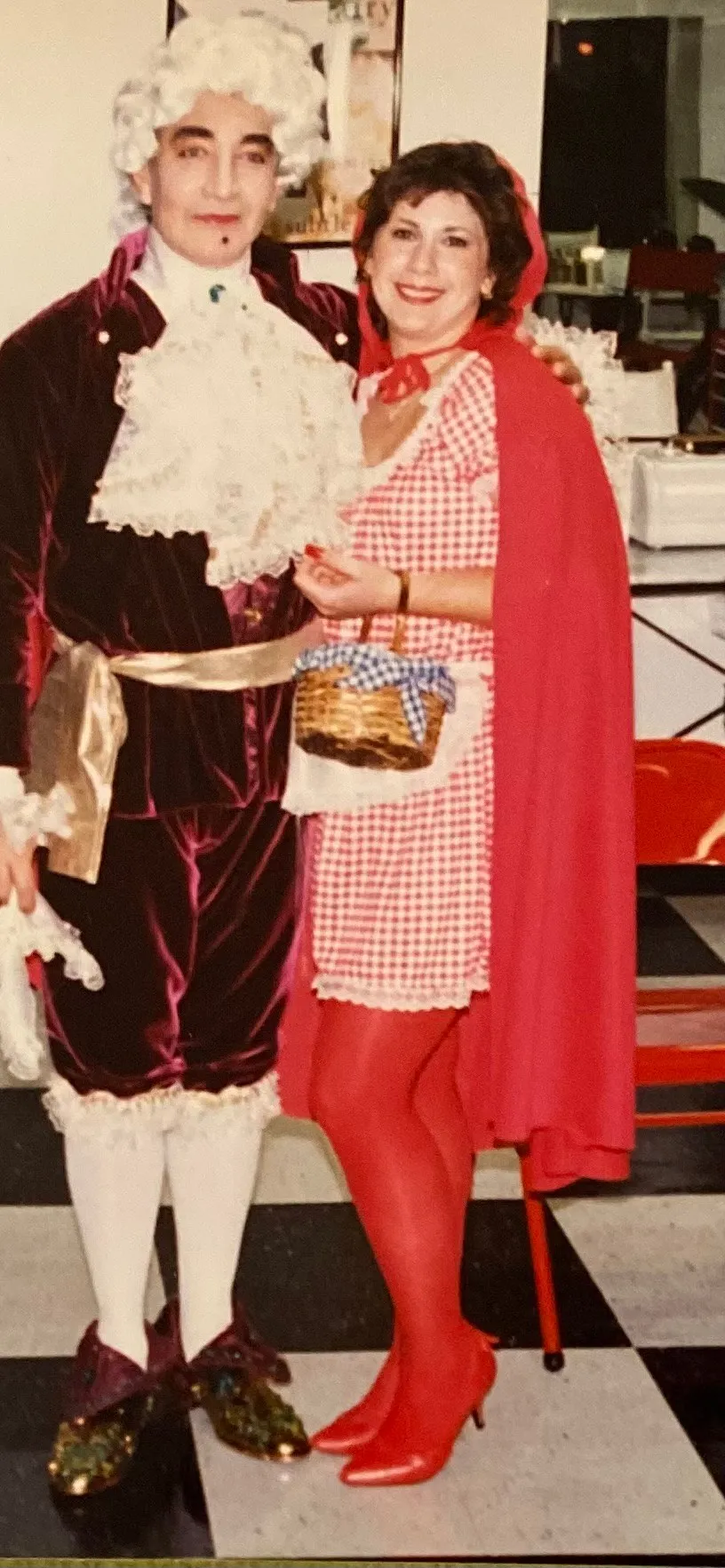 Archival costume party photo of L.A. Monroe co-founder Luis in a powdered wig and velvet aristocrat costume beside a woman dressed as Little Red Riding Hood inside the salon