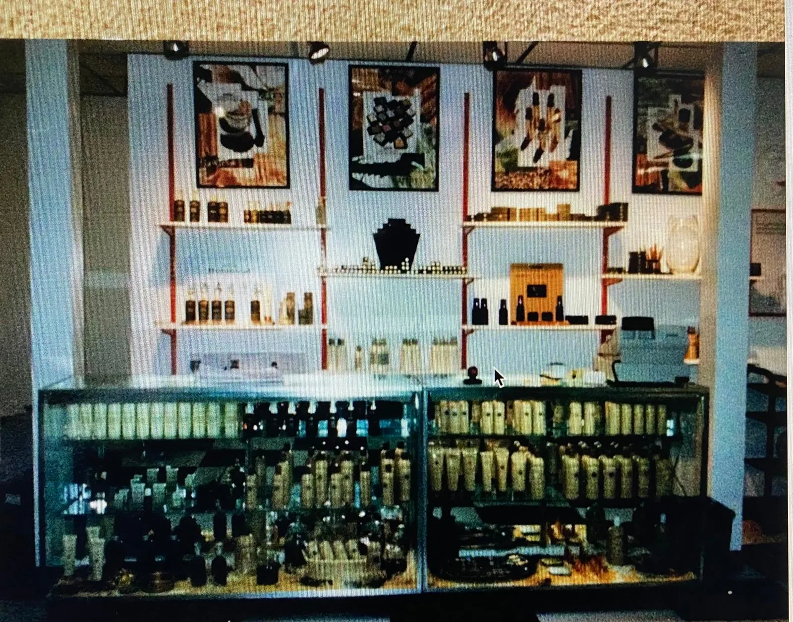 Archival photograph of the L.A. Monroe retail wall - framed editorial prints above shelves of haircare products and glass display cases
