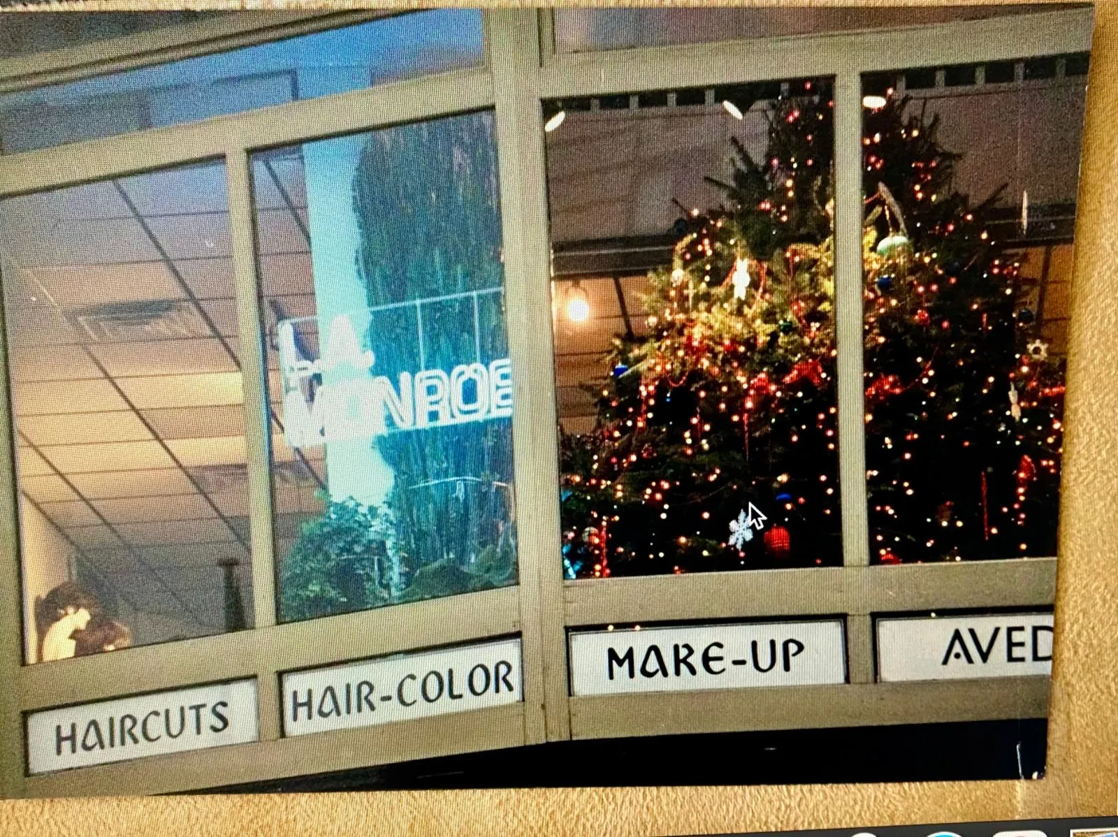 Archival photograph of the L.A. Monroe storefront - HAIRCUTS, HAIR-COLOR, MAKE-UP, AVEDA window decals and a fully decorated Christmas tree inside