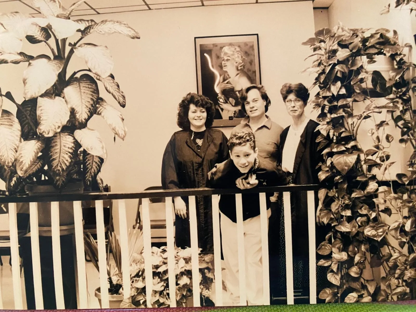 Archival sepia photograph of the L.A. Monroe team gathered behind a striped railing among large plants