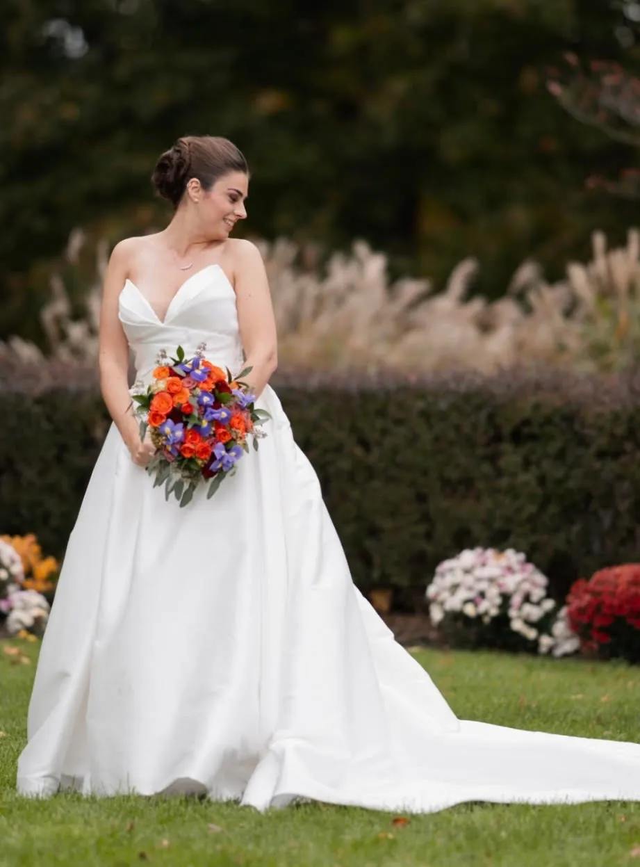 Bride with an elegant updo and soft glam makeup by L.A. Monroe Hair Studio, holding her bouquet in a garden