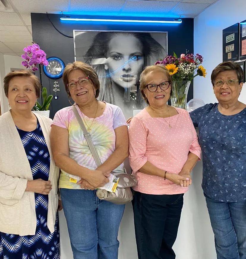Four longtime clients of L.A. Monroe Hair Studio posing together inside the salon in front of the editorial black-and-white portrait wall