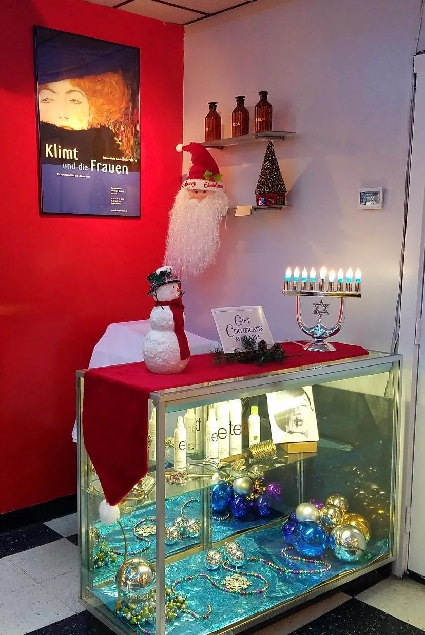 Festive holiday display with a Klimt poster, a menorah, and ornaments above a 'Gift Certificates Available' sign
