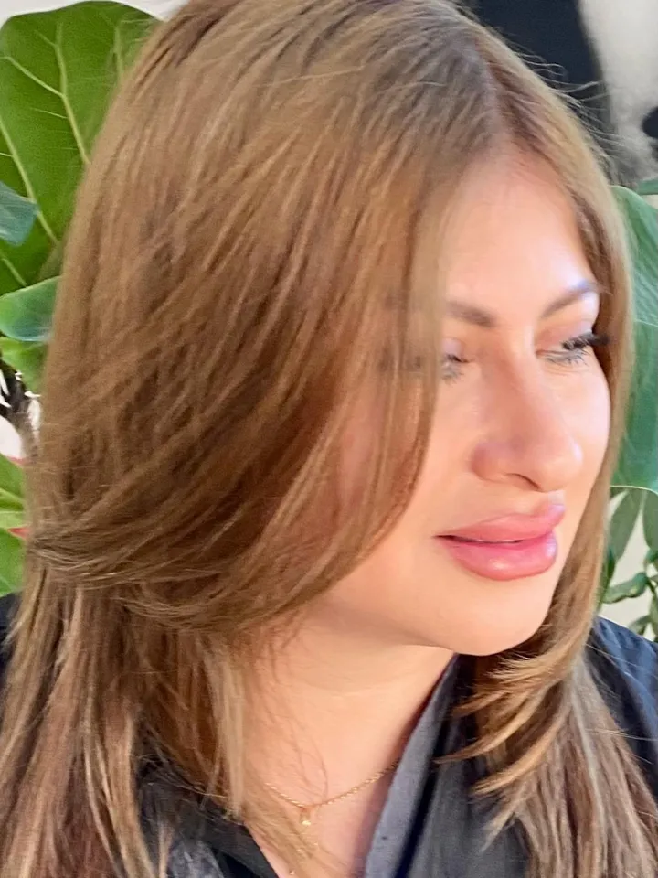 Side profile of a layered honey-brunette cut with soft texture, captured among tropical plants