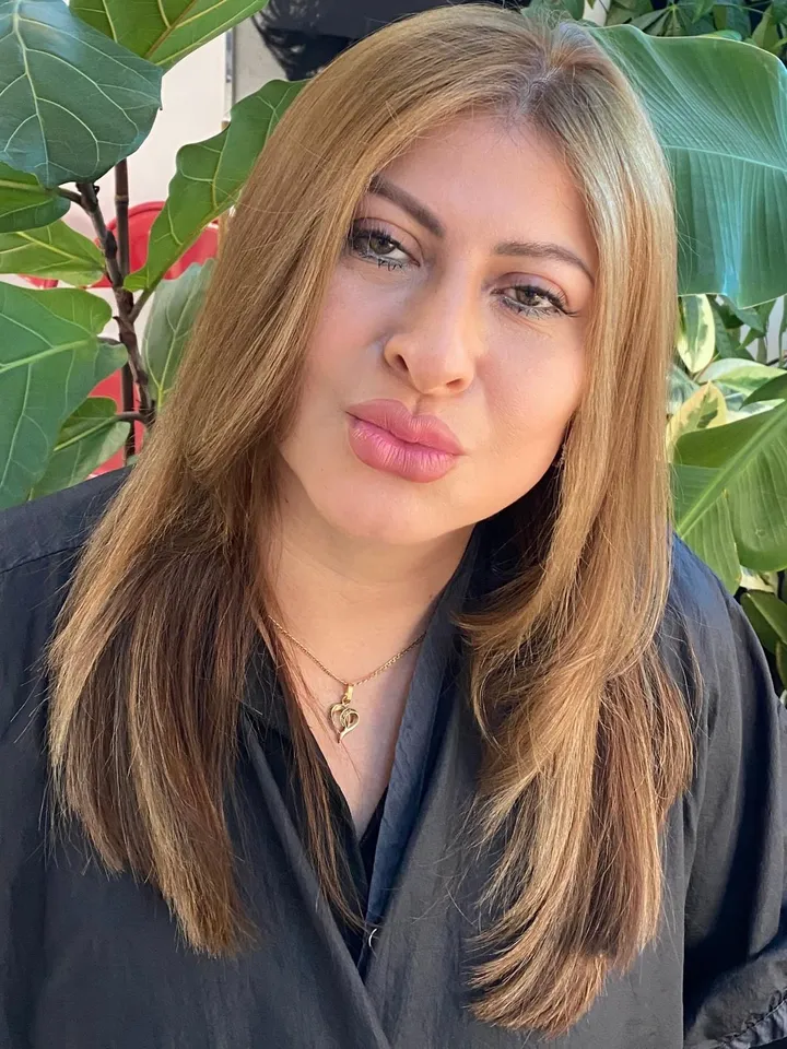 Long sleek honey-brunette hair with subtle highlights, polished portrait among tropical plants