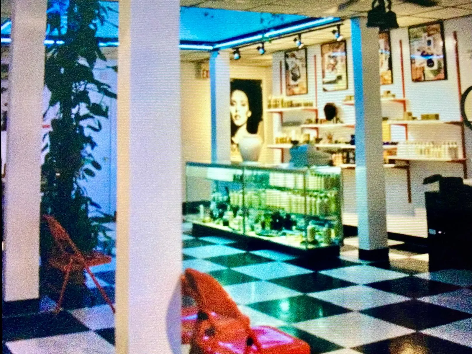 Salon interior with white columns, a checkered floor, and a glass product counter beneath a large portrait artwork
