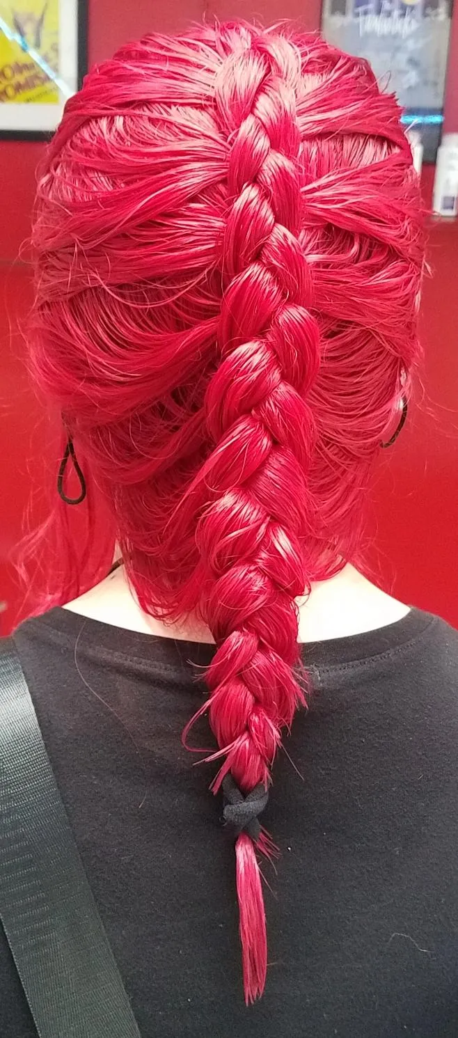 Vibrant magenta-red hair braided into a French braid that transitions into a fishtail